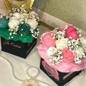 Bouquet personnalisable en cire avec fleurs roses, blanches et vertes, présenté dans une boîte noire décorative avec du gypsophile.